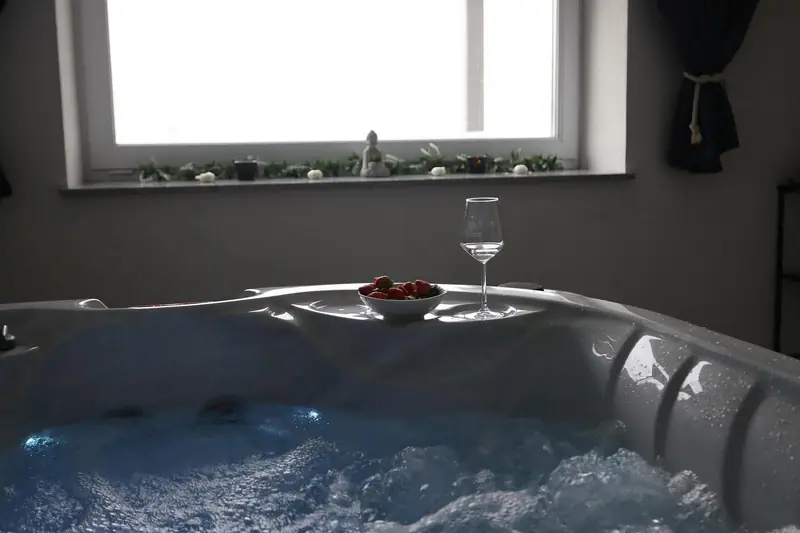 Mehurčki v notranjem jacuzziju, kozarec vina in jagode