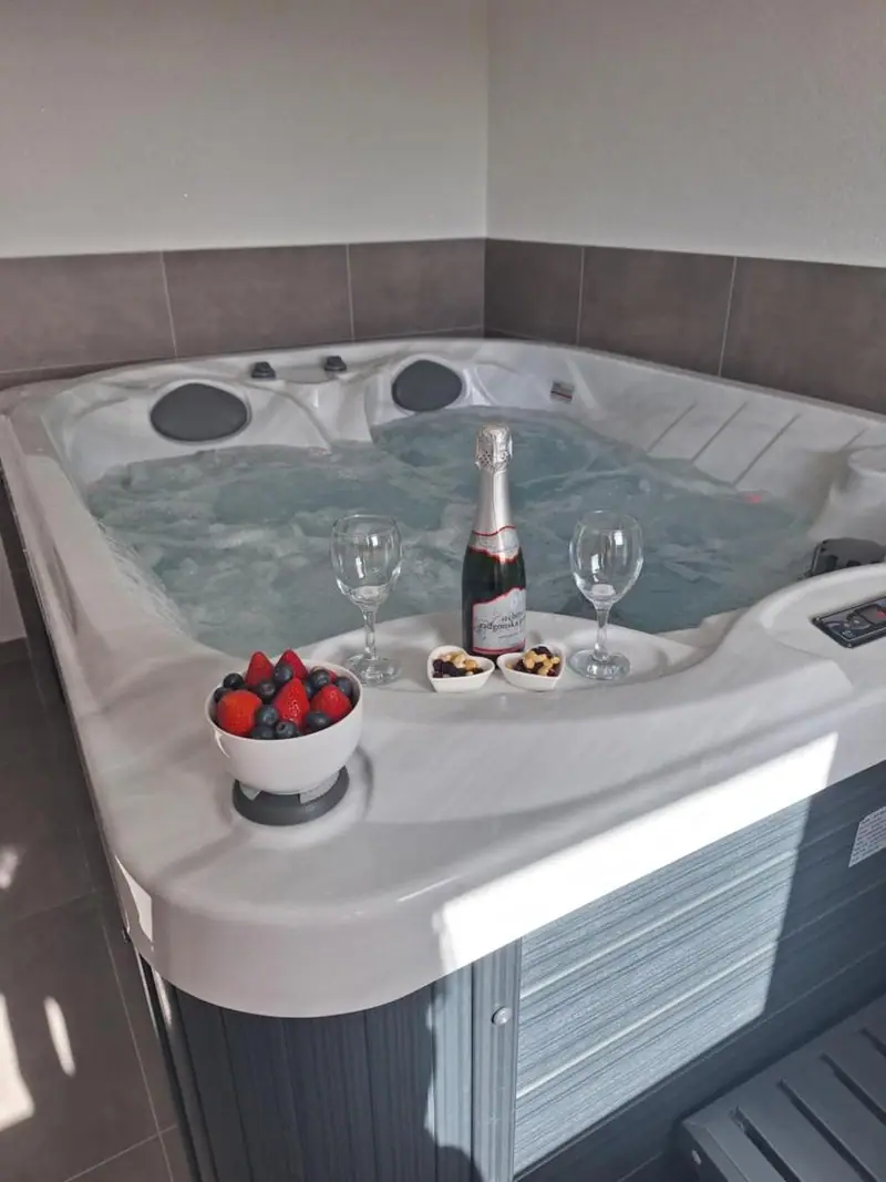 Notranji jacuzzi, pripravljen s penino, dvema kozarcema in jagodami
