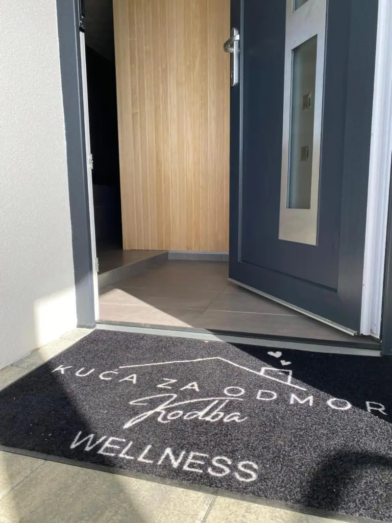 Vhod v hišo s predpražnikom z napisom Kuća za odmor Kodba Wellness